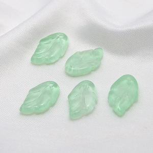 Detailed macro of five translucent light green Czech glass leaf charms for DIY hair ornaments