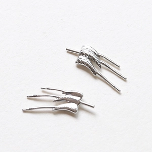 Détail macro de breloques de boucles d'oreilles ailes en argent avec pompons métalliques