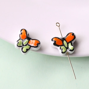Dettaglio macro di perle in ceramica a farfalla dipinte a mano per creazione di gioielli