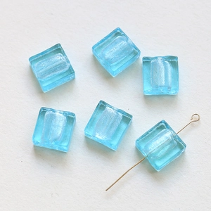 Macro detail of translucent blue square glass beads with silver glitter for DIY jewelry