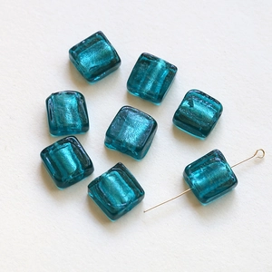 Macro detail of translucent teal square glass beads with silver foil for DIY jewelry making