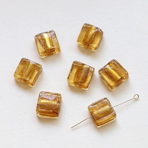 Macro shot of translucent amber glass square beads with gold foil inlay for DIY jewelry