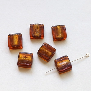 Macro view of translucent amber glass square beads with gold foil foil insert for DIY jewelry