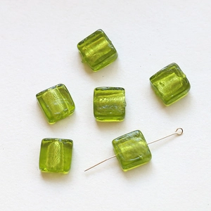 Detailed view of translucent green cube glass beads with gold foil foil inclusions