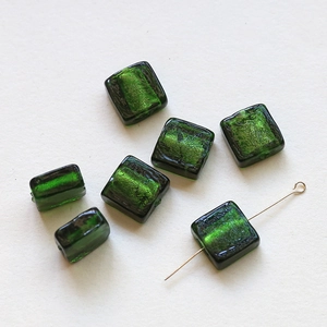 Close-up of translucent dark green glass square beads with inner silver foil for DIY jewelry