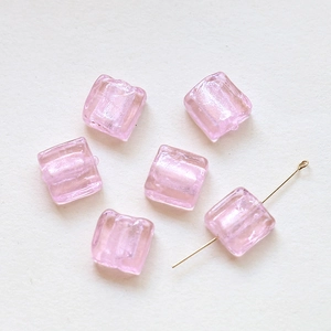 Close-up of translucent pink square glass beads with gold pin for DIY jewelry making