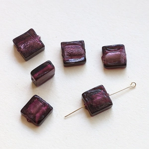 Macro detail of translucent purple square glass beads with golden metal pin for DIY jewelry