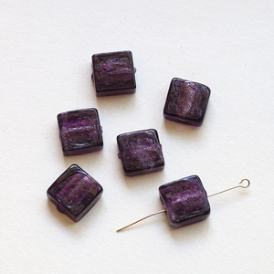 Macro shot of translucent purple square glass beads with inner silver foil for DIY crafts