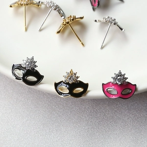 Zirconia mask stud earrings set in gold and silver plating on white porcelain