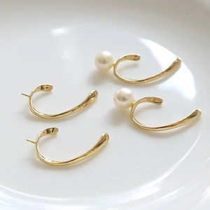 Dettaglio di clip per orecchini placcati oro 18k con perle e texture metallica martellata