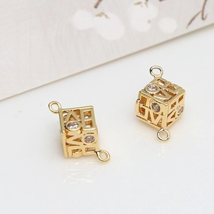 Macro detail of gold-plated LOVE cube charms with cubic zirconia and double ring connectors