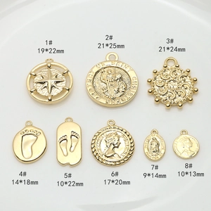 Flat lay of gold charms featuring vintage portraits and celestial symbols for DIY jewelry