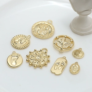 Close-up of assorted vintage gold pendants featuring religious and coin motifs on a tray