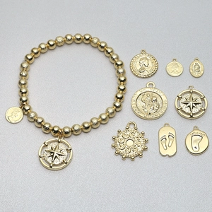 Golden beaded bracelet set with vintage coin charms and religious pendants on grey background