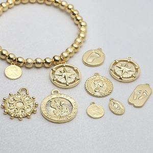 Detailed close-up of vintage gold coin pendants and saint charms on grey fabric background
