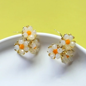 Elegantes pendientes de margarita bañados en oro con pétalos blancos y centro naranja