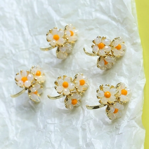 Cinco pendientes de flores chapados en oro con pétalos de opalo y centros naranja