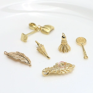 Détails macro de pendentifs dorés en forme de feuille et badminton pour bijoux DIY
