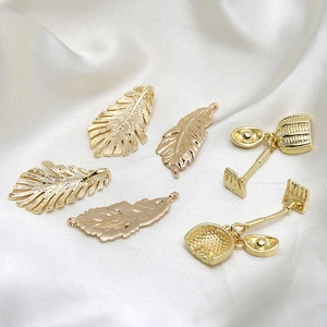 Ensemble de breloques dorées avec feuilles plumes et mini-outils sur soie blanche