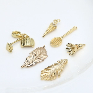 Pendentifs bijoux dorés incluant plume, parapluie et raquettes de sport sur fond blanc