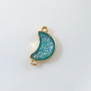 Macro shot of gold crescent moon connector with blue shimmer resin for DIY jewelry
