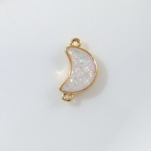 Macro detail of crescent moon pendant connector with iridescent sequins and gold loops