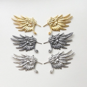 Detailed view of angel wing metal charms in gold, silver, and gunmetal finishes