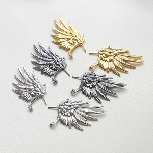 Detailed view of wing-shaped jewelry charms in gold, silver, and antique silver finishes