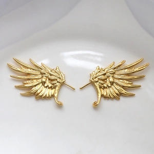 Detailed close-up of gold-plated metal wing jewelry components with realistic feather textures