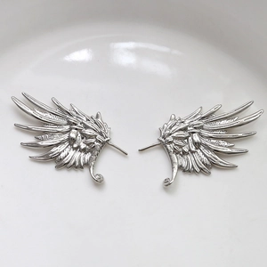 Detailed view of silver wing-shaped earring components with fine feather textures