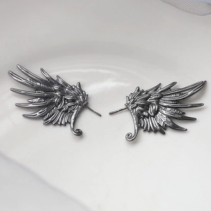 Detail view of gothic black feather wing earrings with intricate metallic texture