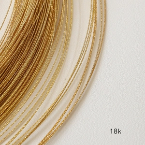 Detalle macro de alambre de cobre bañado en oro 18k con diseño trenzado para joyería DIY
