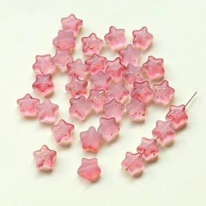 Gros plan de perles en verre rose en forme d'étoile de 8 mm avec paillettes de sable doré