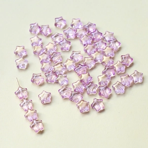 Vue macro de perles en verre violettes de 8 mm en forme d'étoile avec paillettes dorées