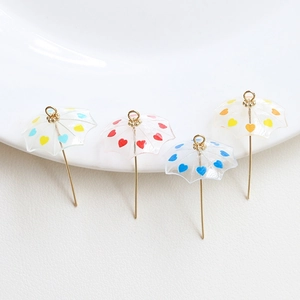 Macro shot of colorful heart-patterned umbrella charms with gold hooks for DIY crafts