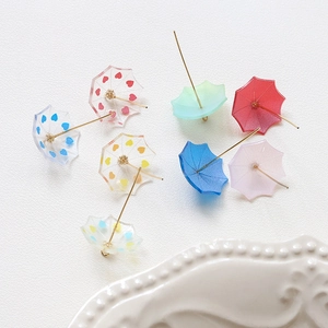 Miniature resin umbrella earrings in multiple colors on elegant white ceramic display