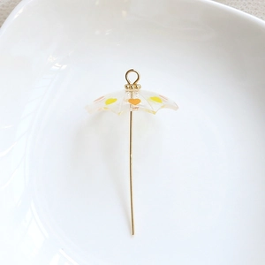 Detail of miniature resin umbrella pendant with orange hearts and gold handle for DIY crafting