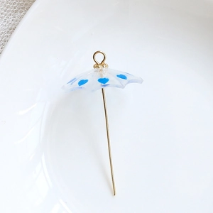 Macro view of transparent umbrella charm with blue heart patterns and golden metal hook