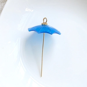 Macro view of blue resin umbrella pendant with golden metal handle for DIY jewelry crafts