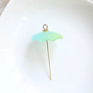 Macro detail of a blue-green gradient resin umbrella pendant with golden metal handle