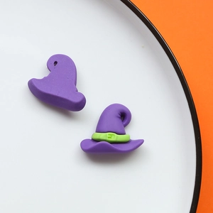 Dettaglio di ciondoli a forma di cappello da strega viola con fibbia verde su sfondo arancione