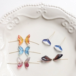 Macro view of gradient resin butterfly wings and whale tail jewelry charms in a ceramic tray