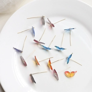 Resin gradient butterfly earrings with translucent wings and gold posts in a ceramic dish