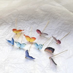 Detailed view of colorful translucent resin butterfly wing charms with golden pins