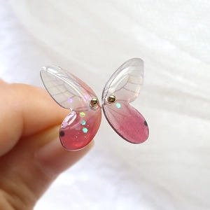 Macro view of gradient resin butterfly wings with glitter and golden metal accents