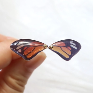 Detailed close-up of resin butterfly wing charms with vibrant orange and black patterns