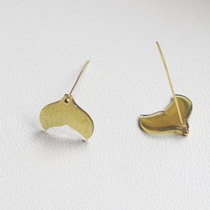 Macro detail of translucent yellow fish tail earrings with shimmering gold glitter