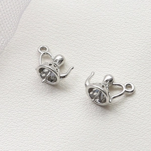 Vue macro de pendentifs théière en métal argenté pour création de bijoux DIY sur cuir blanc