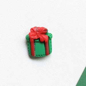 Detailed view of resin Christmas gift box DIY charms with red bow for festive crafts