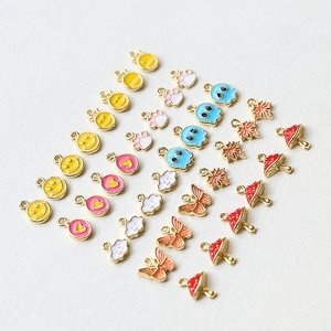 Close-up of colorful enamel charms in butterfly, cloud, and smiley face shapes for DIY jewelry